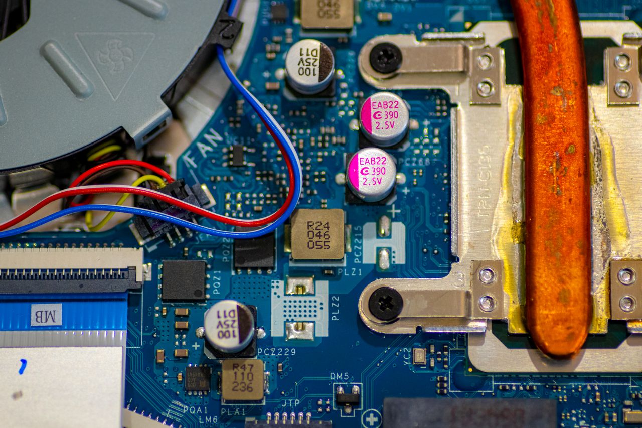 Offerings Detailed image showing circuitry and components on a computer motherboard with wires and capacitors.